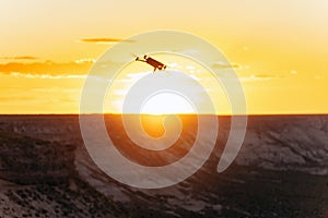 Drone in epic flight against dramatic golden sunset in remote location by the desert cliffs