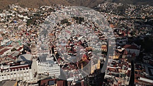 Drone flies above Guanajuato city center in Mexico during daytime: catholic church, university buildings