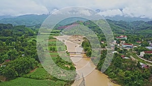 Drone Flies along River Running among Tropical Landscape