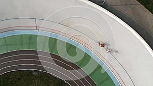 Drone flies around velodrome in Kyiv. Professional cycling team training on cycling track.  Young sportive men on track bikes ridi