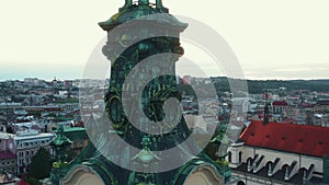 Drone flies close to Latin Cathedral spire in Lviv, Ukraine revealing sunset over authentic old town cityscape skyline.