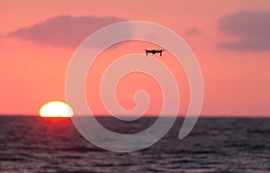 Drone flies over a colourful sunrise sky.