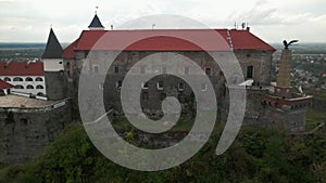 Drone flies over medieval castle on mountain in small european city at cloudy autumn day