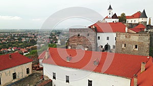 Drone flies over medieval castle on mountain in small european city at cloudy autumn day