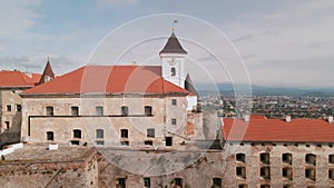 Drone flies over medieval castle on mountain in small european city at cloudy autumn day
