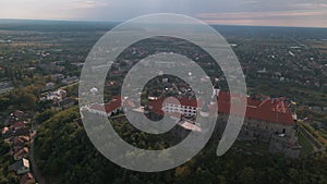 Drone flies over medieval castle on mountain in small european city at cloudy autumn day