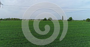 The drone flies over a small country road. There are fields and green trees around.