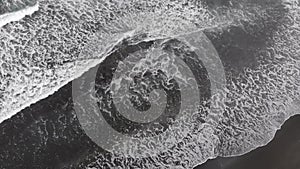 The drone flies over the waves at the seaside. Dramatic view - big dark waves crash on the sandy beach