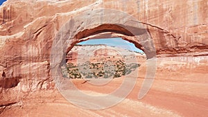 Drone Flies Through Red Orange Stone Arch With Massive Rock Formations In Utah