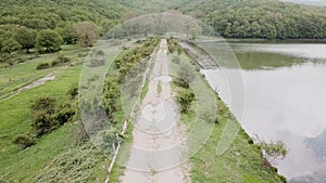 Drone flies on a rural road that runs along a lake