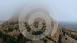 Drone flies up to the top of Devil`s Tower rock in Wyoming, the top of is hiding in the clouds