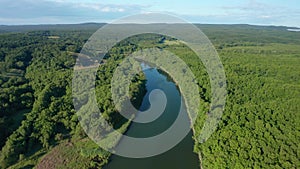 Drone flight above wide river surrounded by green forest