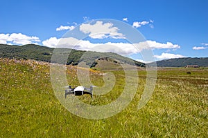 Drone in flight hovering in a flowery field in the spring in the mountains. Aerial shots and selfies with the drone. Control and