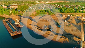 Drone flight over the sand and gravel mining on a sunny summer day near the river. Scene. Concept of heavy industry and