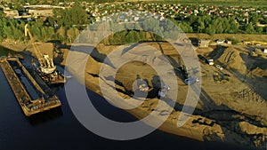 Drone flight over the sand and gravel mining on a sunny summer day near the river. Scene. Concept of heavy industry and