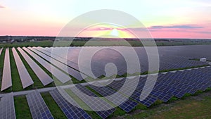 Drone fly over Solar Farm. Renewable green energy and electrical technology. Field of Solar Panels Stands in a Row in