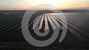 Drone fly over Solar Farm. Renewable green energy and electrical technology. Field of Solar Panels Stands in a Row in