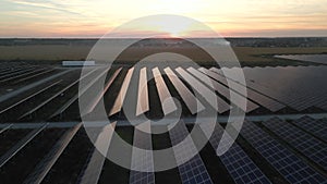 Drone fly over Solar Farm. Renewable green energy and electrical technology. Field of Solar Panels Stands in a Row in