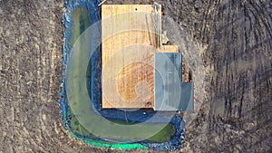 Drone fly up above construction of new building with small pond in spring, aerial