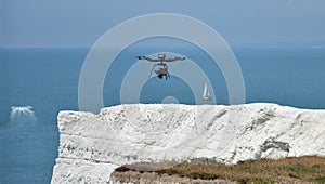 Drone flying above cliffs with boats in background