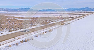 DRONE: Flying along a silver car cruising down the empty highway crossing Utah.