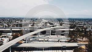 Drone flying backwards over large highway interchange in Los Angeles, USA with traffic moving through many road levels.