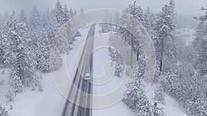 DRONE Flying behind a car driving through a snowstorm as commuter drives to work