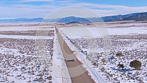 DRONE: Flying behind a silver car driving along highway running across Montana