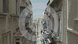 Drone flying forward on narrow beautiful old street,Valletta,Malta . Old, vintage windows, balconies. - 4K