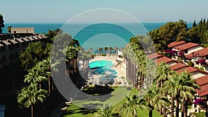 Drone flying low above pleasure dome hotel resort with beautiful pool to idyllic summer sea coast beach at Side, Turkey.