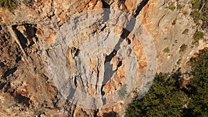 drone flying out from limestone cliff with rock climber on it. man climbs challenging route on vertical crag