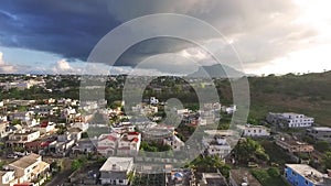 Drone flying over the Belle Etoile town in Mauritius, close to Port Louis. Stormy Sky and mountain in Background