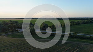 Drone flying over hay bales at agricultural field at sunset or sunrise