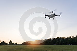 Drone flying over landscape. UAV drone copter flying with digital camera. Drone flying overhead in cloudy blue sky. Quad copter is