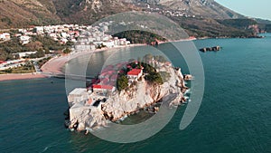 Drone flying over the rocky Sveti Stefan island, surrounded by Adriatic coast. Balkans, Montenegro, Europe