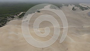 Drone flying over sand dunes with woman seen running down dune