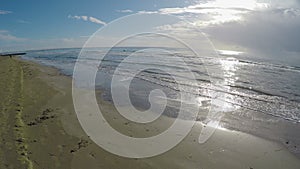 Drone flying over sandy beach, sea waves washing ashore, sunny weather, Cyprus