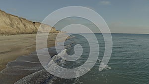 A drone flying over a sandy seashore on a cloudy