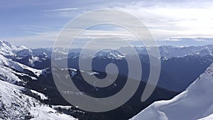 Drone flying over snowboarders standing on snow peak of winter mountains