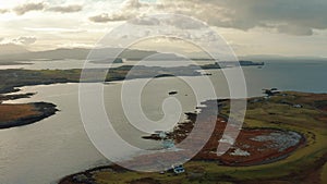 Drone flying over still calm reflective lake during sunrise in Isle of Skye