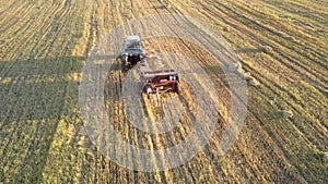 Drone follows tractor baler pushes up straw bale on field