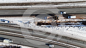 Drone footage of construction workers laying new sewage pipes near a road during winter day