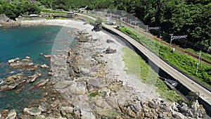 Drone footage of narrow road with trees behind the shoreline