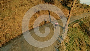 Drone footage of woman cyclist in sunset on bike