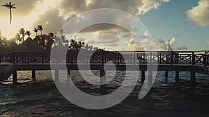 Drone footage of wooden pier jetty over lagoon ,palms on beach and cloudy sky background, evening , sunset. Bavaro
