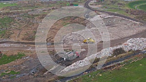 DRONE: Garbage truck parked by a pile of debris near a large industrial junkyard