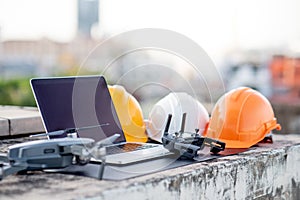 Drone, laptop and protective helmet at construction site