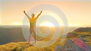 DRONE, LENS FLARE: Bright evening sun rays shine on the victorious male hiker.