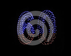 Drone light shows on black night sky background. A figure of the number sixty, six, zerro, 60 made of glowing drones.