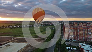 Drone moves around air balloon. Cinematic evening landscape with dramatic sky